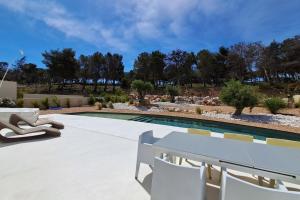 een terras met een zwembad en een witte tafel en stoelen bij Casa Bianca - Villa d'architecte avec piscine in Leucate +27 foto's
