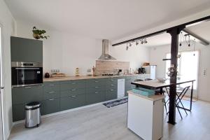 a kitchen with green cabinets and a table in it at L'évasion des Corbières in Portel-des-Corbières +9 photos