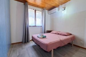 a bedroom with a bed with pink sheets and a window at L'évasion des Corbières in Portel-des-Corbières