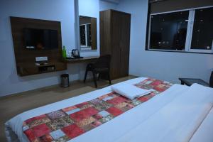 Un dormitorio con una cama con una colcha encima en Hotel Alento, en Jamnagar