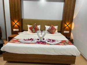 una cama con dos cisnes hechos de flores en Hotel Alento, en Jamnagar
