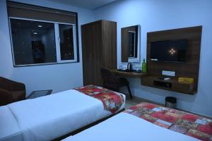 Una habitación de hotel con dos camas y un televisor. en Hotel Alento, en Jamnagar