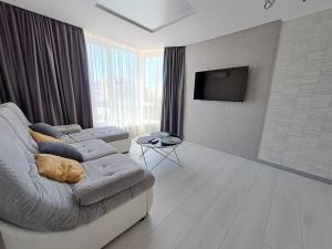 Apart Premium ЖК Андріївський في ترنوبل: غرفة معيشة مع أريكة وتلفزيون بشاشة مسطحة