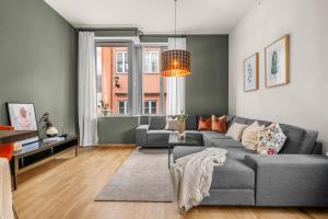 Midtbyen Apartment في تروندهايم: غرفة معيشة مع أريكة رمادية ونافذة
