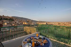a table on a balcony with a view of a city at Dar El Kendil in Fez