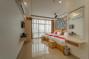 a bedroom with two beds and a large window at Priya Residency Pondicherry in Pondicherry
