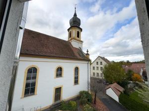 a white church with a steeple on top of it at Ferienwohnung zum Kirchturmblick in Dettelbach