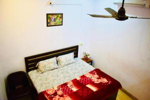 a bedroom with a bed with a red and white comforter at Radha Krishna Paying Guest House in Ayodhya