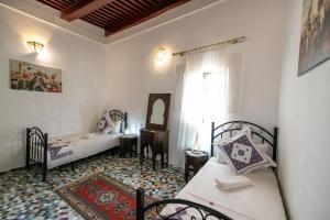een kleine kamer met twee bedden en een spiegel bij Dar El Kendil in Fès
