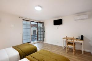 Un dormitorio con una cama y un escritorio con una mesa. en Df Alojamentos e Suites, en Eiras