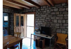 a living room with a table with a tv and a stone wall at Tsarouxi village 2 in Drakótrypa