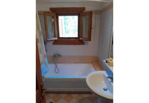 a bathroom with a tub and a sink and a window at Tsarouxi village 2 in Drakótrypa +6 photos