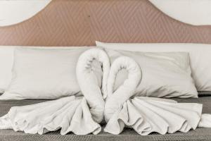 Dos cisnes de toalla sentados encima de una cama en Unique Apartahotel 3-3, en Torrevieja