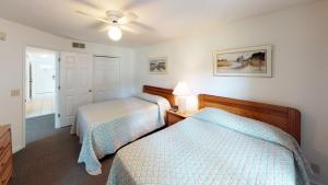 Club Villas Unit 2B في صن سيت بيتش: غرفة نوم بها سريرين ومروحة سقف