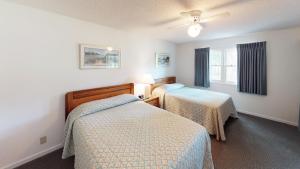 Club Villas Unit 2B في صن سيت بيتش: غرفة نوم بها سريرين ومروحة سقف