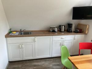 una cucina con mobili bianchi, un lavandino e un tavolo di Finn-Ida a Zinnowitz