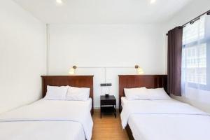 two twin beds in a room with a window at Taladnoi Paint House in Bangkok