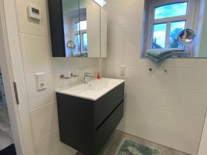 Ferienwohnung im Gulfhof, 65269 في Moormerland: حمام أبيض مع حوض ومرآة +20 صورة