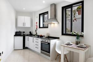 cocina con armarios blancos, mesa y fogones en Mi Casa Es Su Casa Nº2, en Albufeira