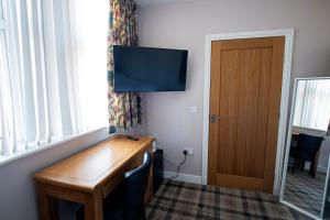 a room with a wooden desk with a television on the wall at Poseidon's in Lossiemouth