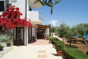 a house with red flowers and a walkway at Apartmani Braco Caratan in Zavala