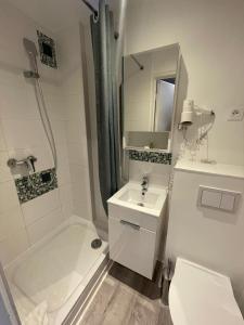 a white bathroom with a sink and a shower at Hôtel les Coulisses in Forbach