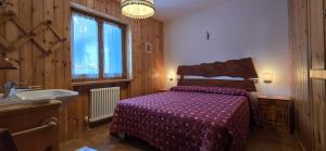 a bedroom with a bed and a sink and a tub at Casa Vaiolet in Pozza di Fassa