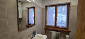 a bathroom with a sink and two windows and a mirror at Casa Vaiolet in Pozza di Fassa