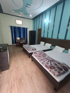 zwei Betten in einem Zimmer mit Holzboden in der Unterkunft Treat Hotel And Restaurant in Naimishāranya