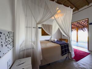 Pousada e camping Filó Caraíva في بورتو سيغورو: غرفة نوم مع سرير مظلة مع ستائر بيضاء +82 صورة
