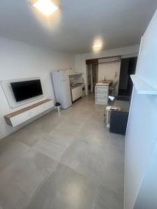 an empty living room with a television and a kitchen at Espacio Centro in La Plata +8 photos