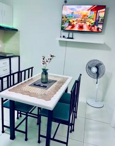 a dining room table with chairs and a tv on the wall at Naga City River View 2BR UB Apartment in Naga
