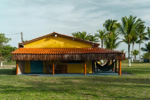 Pousada e camping Filó Caraíva في بورتو سيغورو: منزل أصفر أمامه أرجوحة