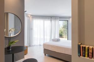 Villa Artemis في Ágios Stéfanos: غرفة نوم بها سرير ومرآة ونافذة