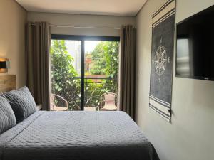 a bedroom with a bed and a large window at Pousada Maritimus in Barretos