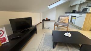a living room with a flat screen tv and a chair at Atico Finisterre in Fisterra