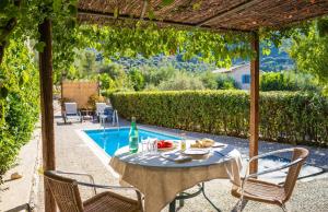 a table and chairs next to a swimming pool at Amalthia Cottage in Vathi, Ithaka