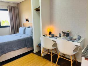 a bedroom with a bed and a desk with two chairs at Pousada Maritimus in Barretos