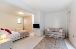 Villa Akoni في ميغانيسي: غرفة نوم بيضاء مع سرير وأريكة