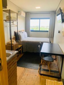 a small room with a bed and a table at Pousada Maritimus in Barretos