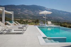 a swimming pool with lounge chairs and an umbrella at Villa Stellina in Karavádhos