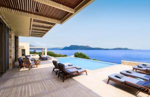 een terras met stoelen en een zwembad bij Villa Noesis in Katomérion