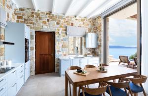 een keuken met een tafel en stoelen en een groot raam bij Villa Noesis in Katomérion