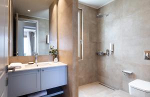 een badkamer met een wastafel, een toilet en een spiegel bij Villa Noesis in Katomérion