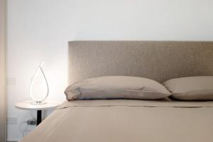 ein Bett mit zwei Kissen und einer Lampe auf einem Tisch in der Unterkunft Casa vacanze Cavalca l'Onda in Poggio
