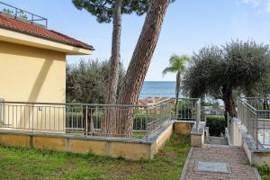 eine Palme neben einem Gebäude mit dem Meer in der Unterkunft Casa vacanze Cavalca l'Onda in Poggio