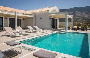 a swimming pool with chairs and a house at Villa Anelle in Karavádhos
