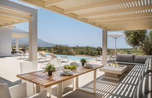 a patio with a table and chairs and a pool at Villa Anelle in Karavádhos