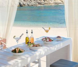 a table with plates of food and a view of the beach at Sivota Senses - Villa Loukas in Sivota
