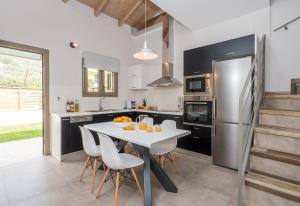La cuisine est équipée d'une table et de chaises blanches ainsi que d'un réfrigérateur. dans l'établissement Acqua Di Mare - Villa Bella, à Nydri